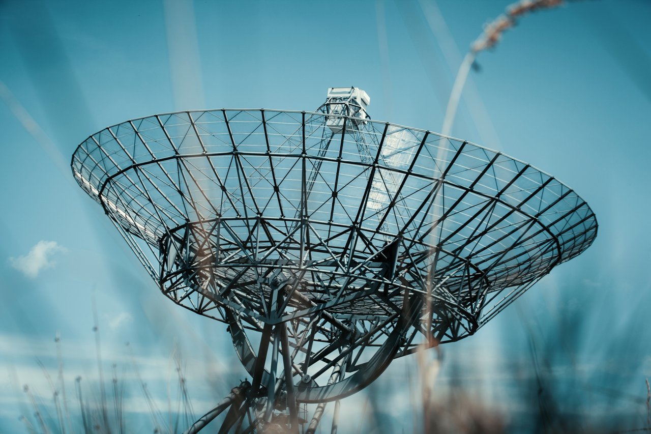A large satellite dish tower set against a clear blue sky, symbolizing communication technology.